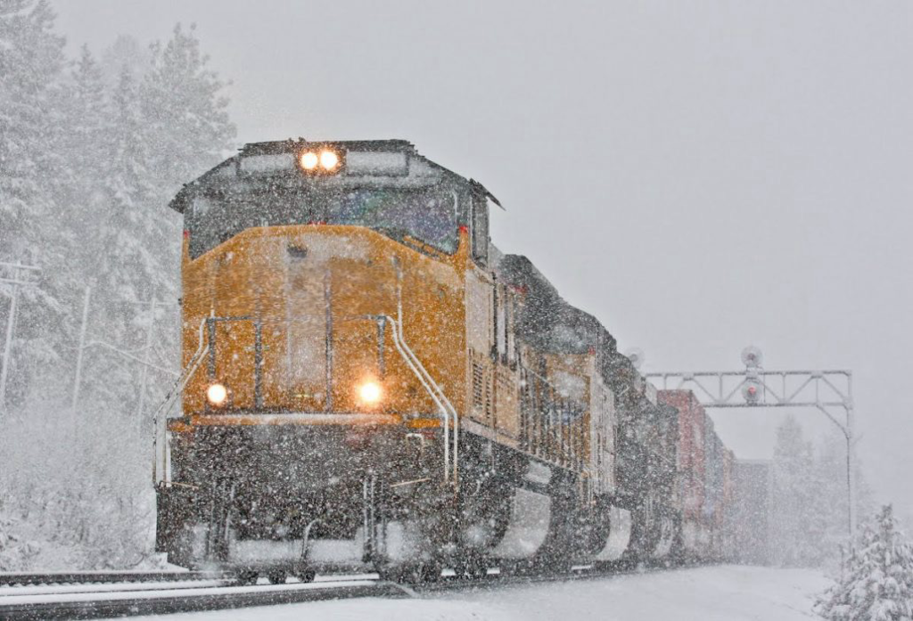 A train traveling down the tracks in the snow